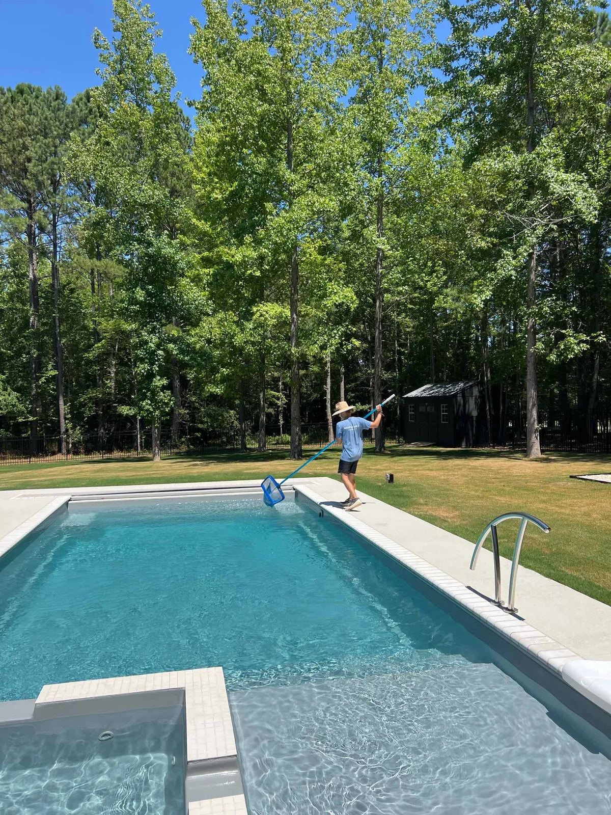 A Pool Collective technician skimming a residential pool